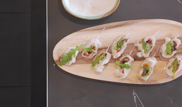 Rollito de bacalao ahumado con pimientos del piquillo, pipas de calabaza, rúcula y aceite de trufa