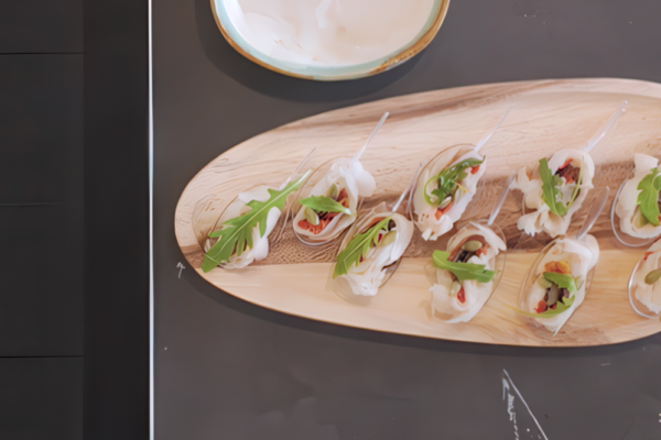 Rollito de bacalao ahumado con pimientos del piquillo, pipas de calabaza, rúcula y aceite de trufa